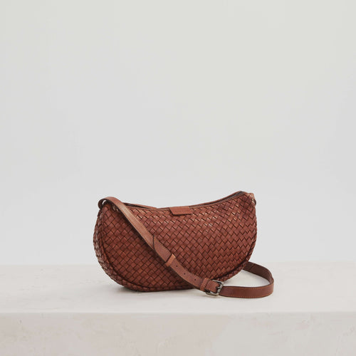 Basque sling crossbody bag in amber from Juju and Co. Woven leather,  cognac, adjustable strap, zip top.